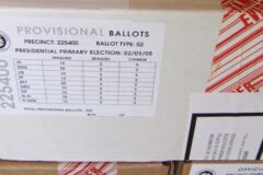 A cardboard box labeled Provisional Ballots, with a precinct number and a ballot count table, sealed with red tamper-evident tape.
